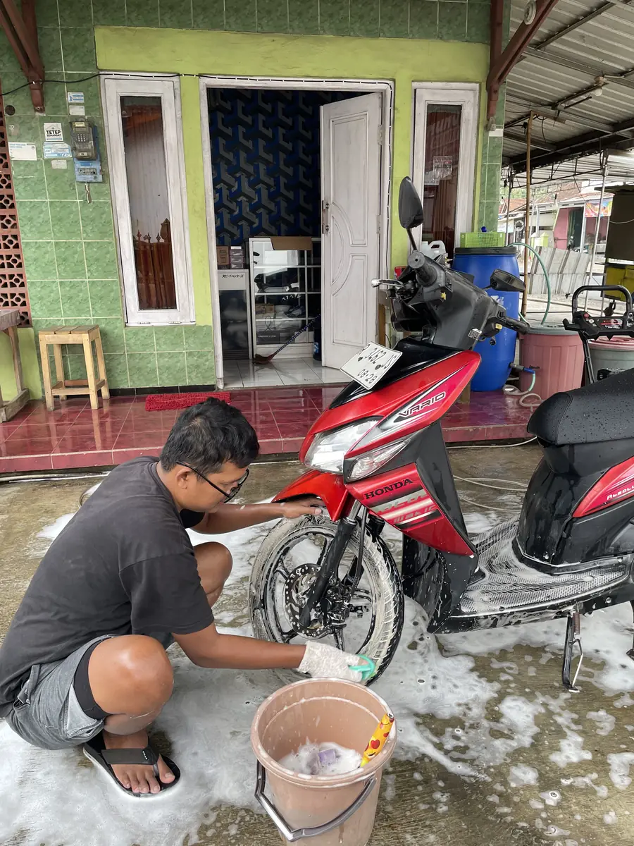 Petugas BAGAS WASH menyabuni roda motor