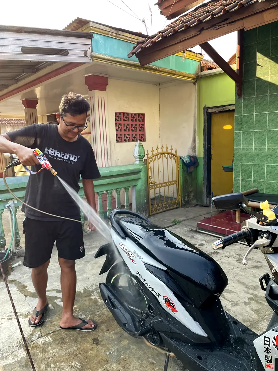 Petugas BAGAS WASH menyemprot motor dengan air